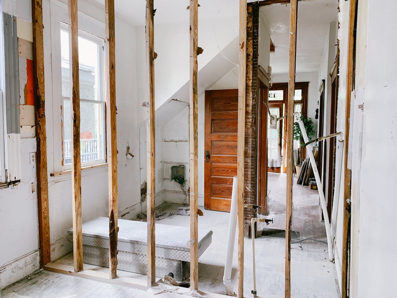 about-01 Interior view of a home under renovation with exposed wooden beams and door.